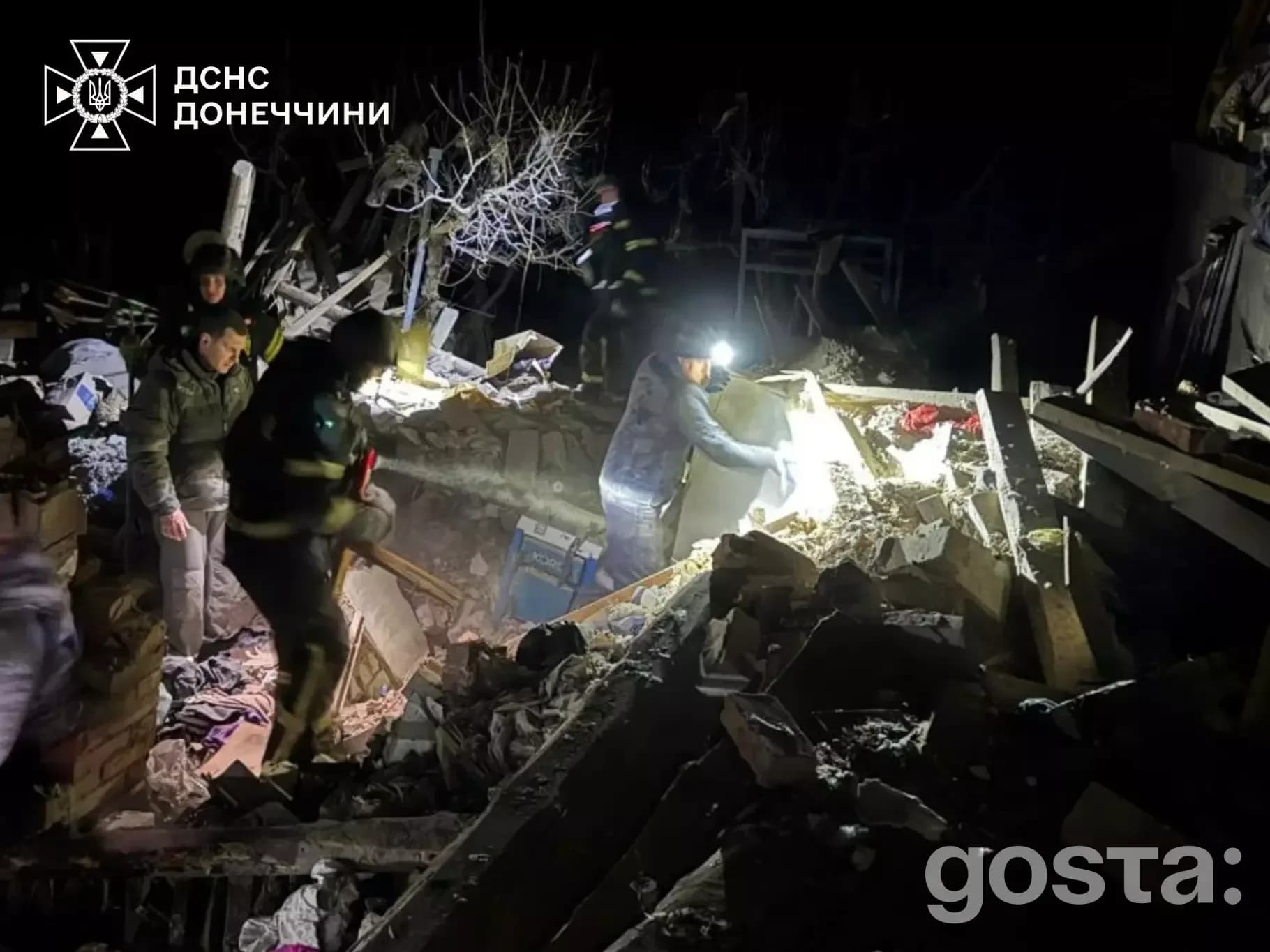 Рятувальники працюють на місці обстрілу в Донецькій області, 13 лютого 2026, зруйновані будівлі та нічний пейзаж.