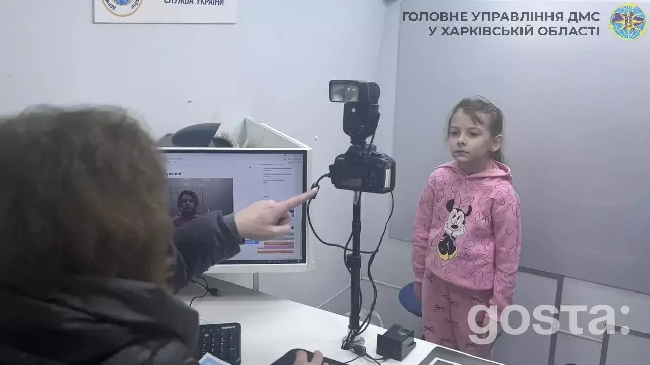 Дитина у рожевому одязі подає біометричні дані в мобільному підрозділі Державної міграційної служби України.