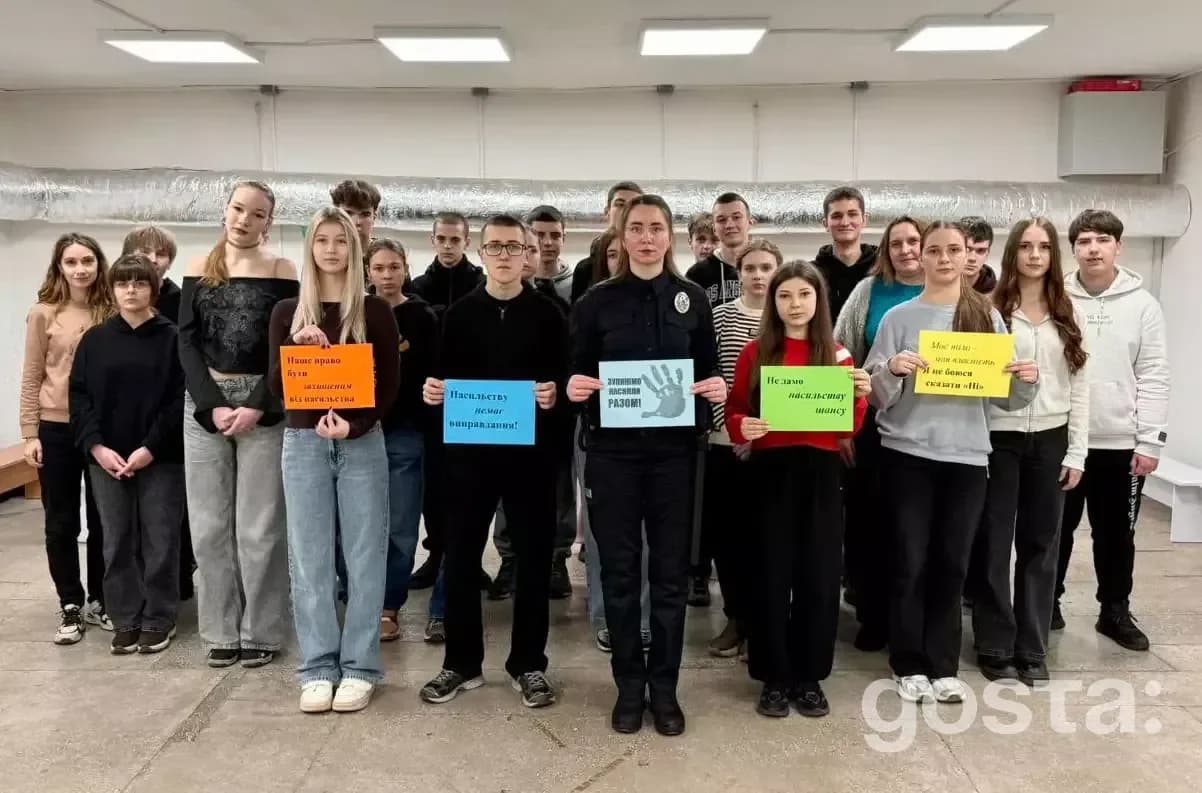 Групове фото учнів і поліцейської Наталії Лисенко тримають таблички проти булінгу, зняте у навчальному закладі.