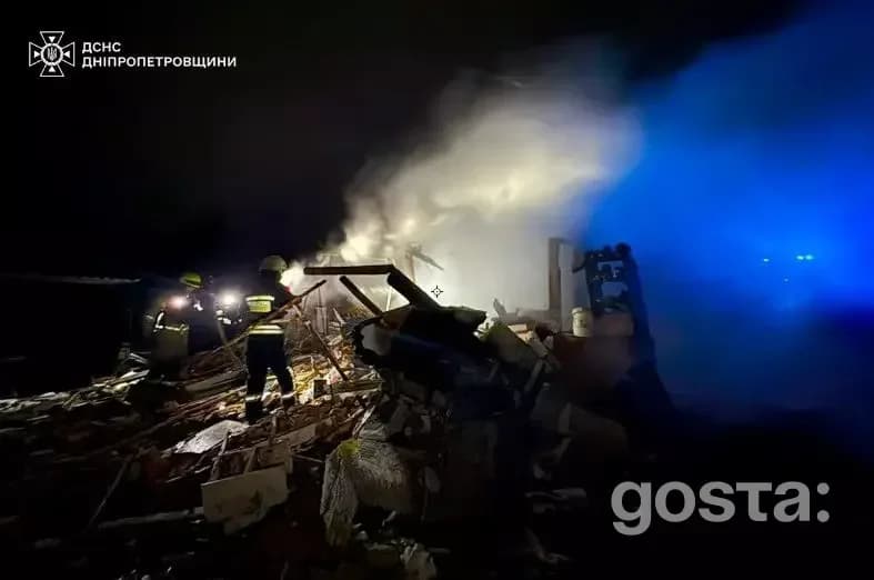 Рятувальники гасять пожежу на руїнах пошкодженої інфраструктури вночі після обстрілів в Україні.