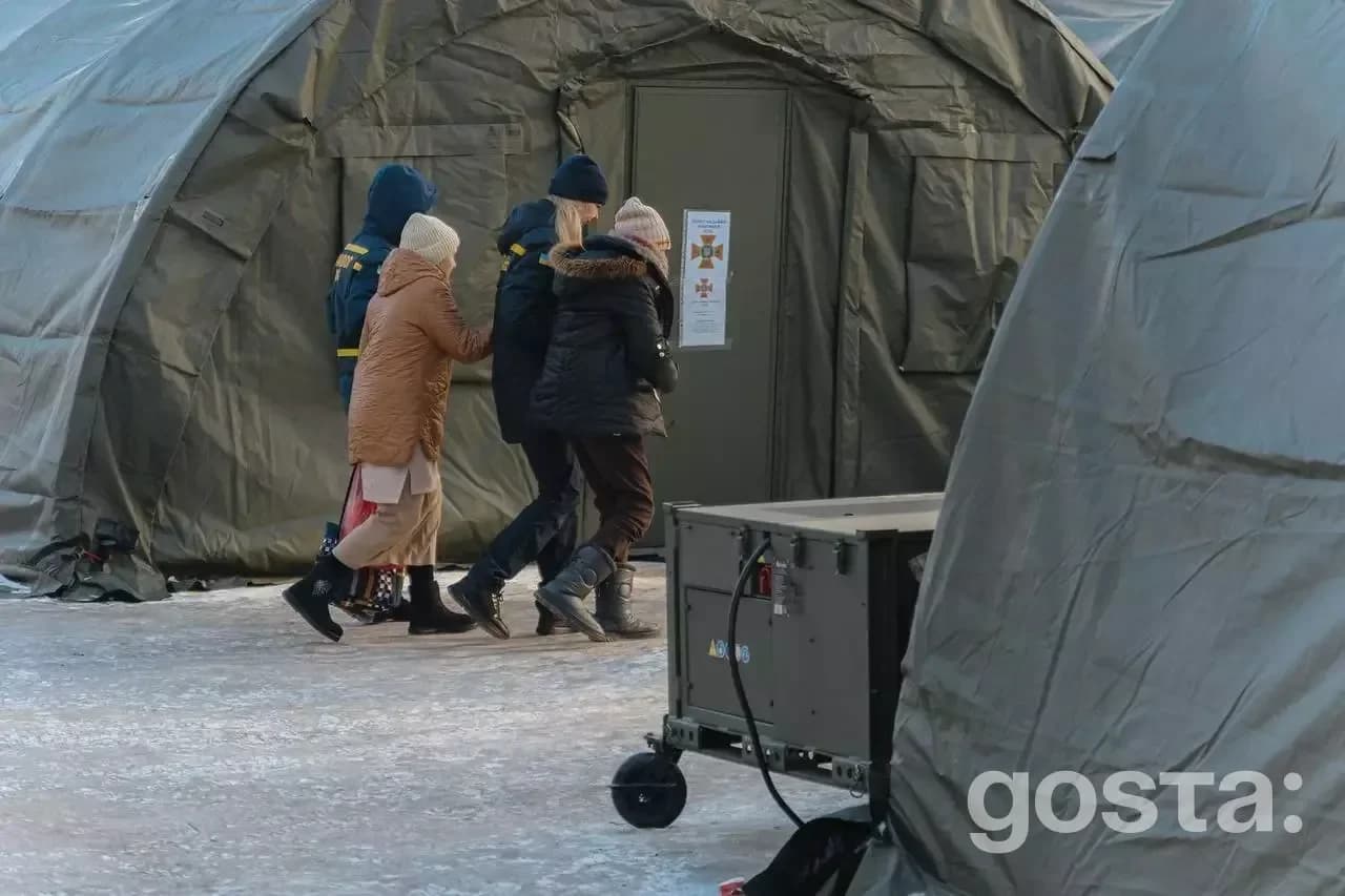 На зображенні люди входять до намету обігріву взимку для захисту від морозу в умовах гуманітарної кризи.