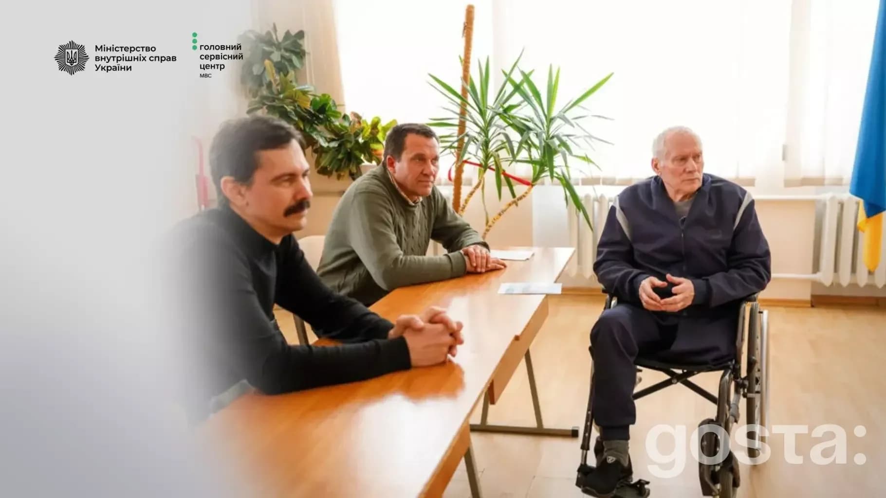 Три чоловіки на зустрічі в сервісному центрі МВС, один у інвалідному візку, обговорюють безбар'єрні автошколи.