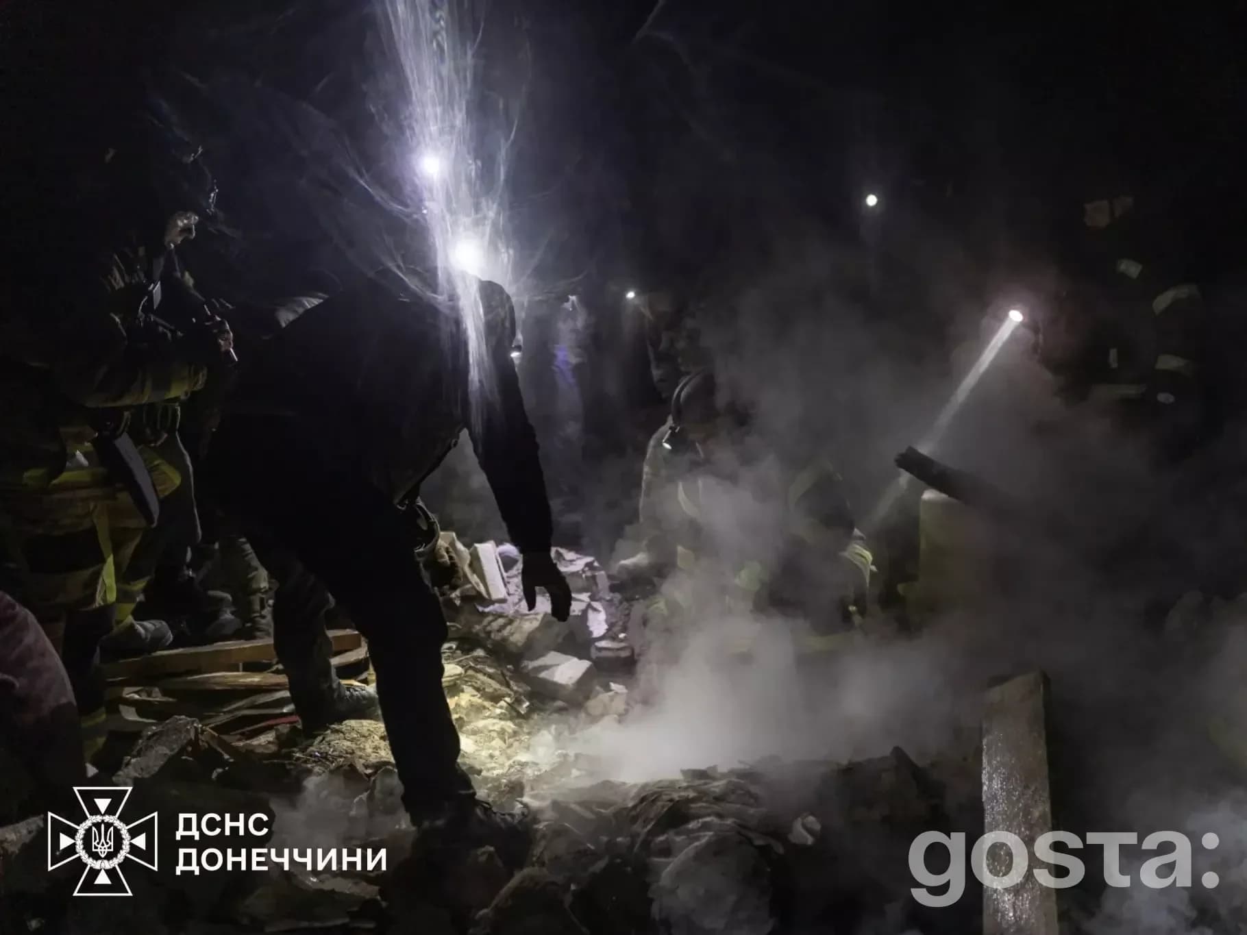 Рятувальники серед уламків будівель під час нічних атак РФ на Донеччині, видно інтенсивну роботу ліхтарів.