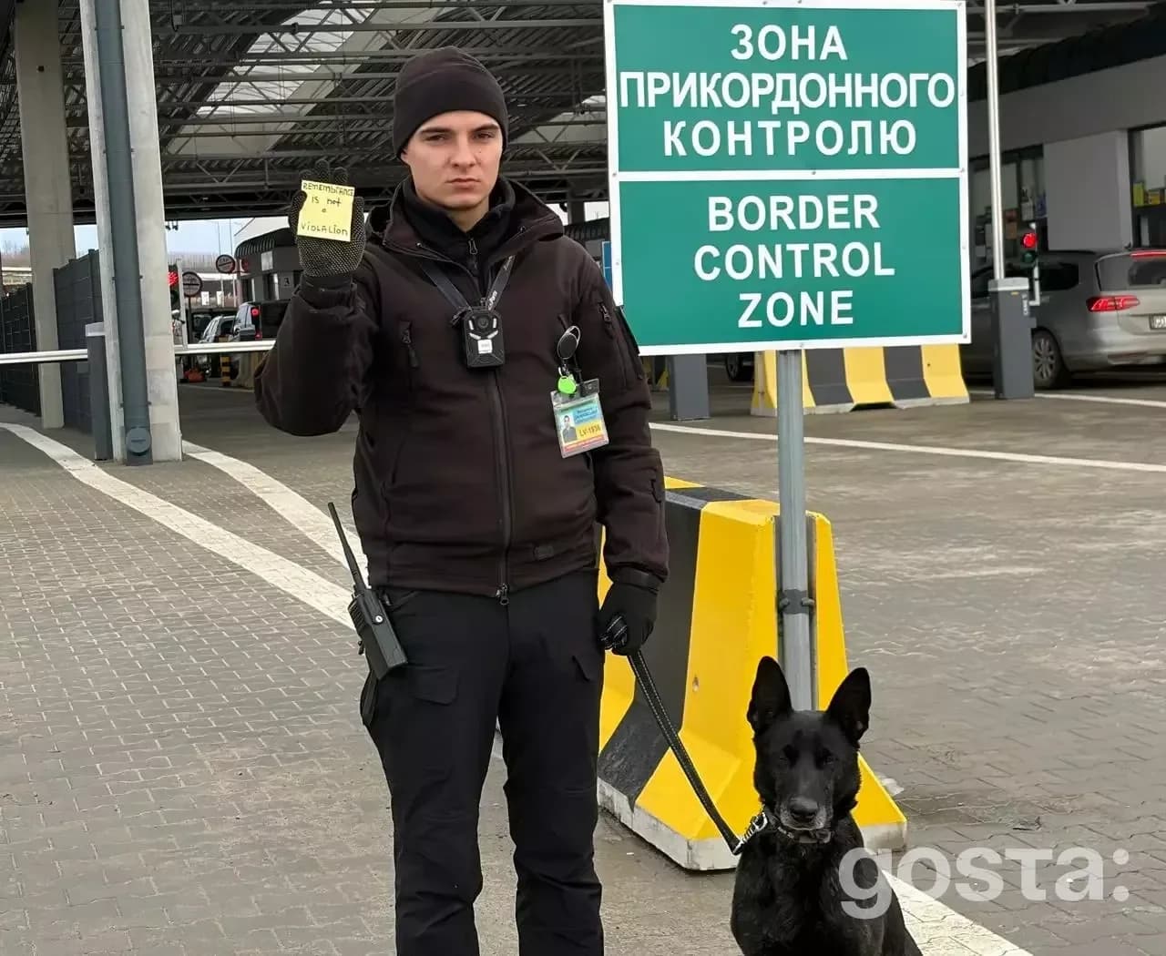 Співробітник прикордонного контролю з собакою стоїть біля знаку "Зона прикордонного контролю".