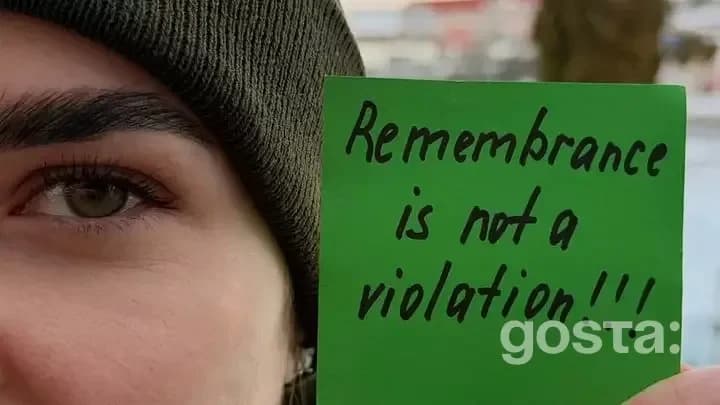 Особа тримає зелений знак із написом "Remembrance is not a violation".