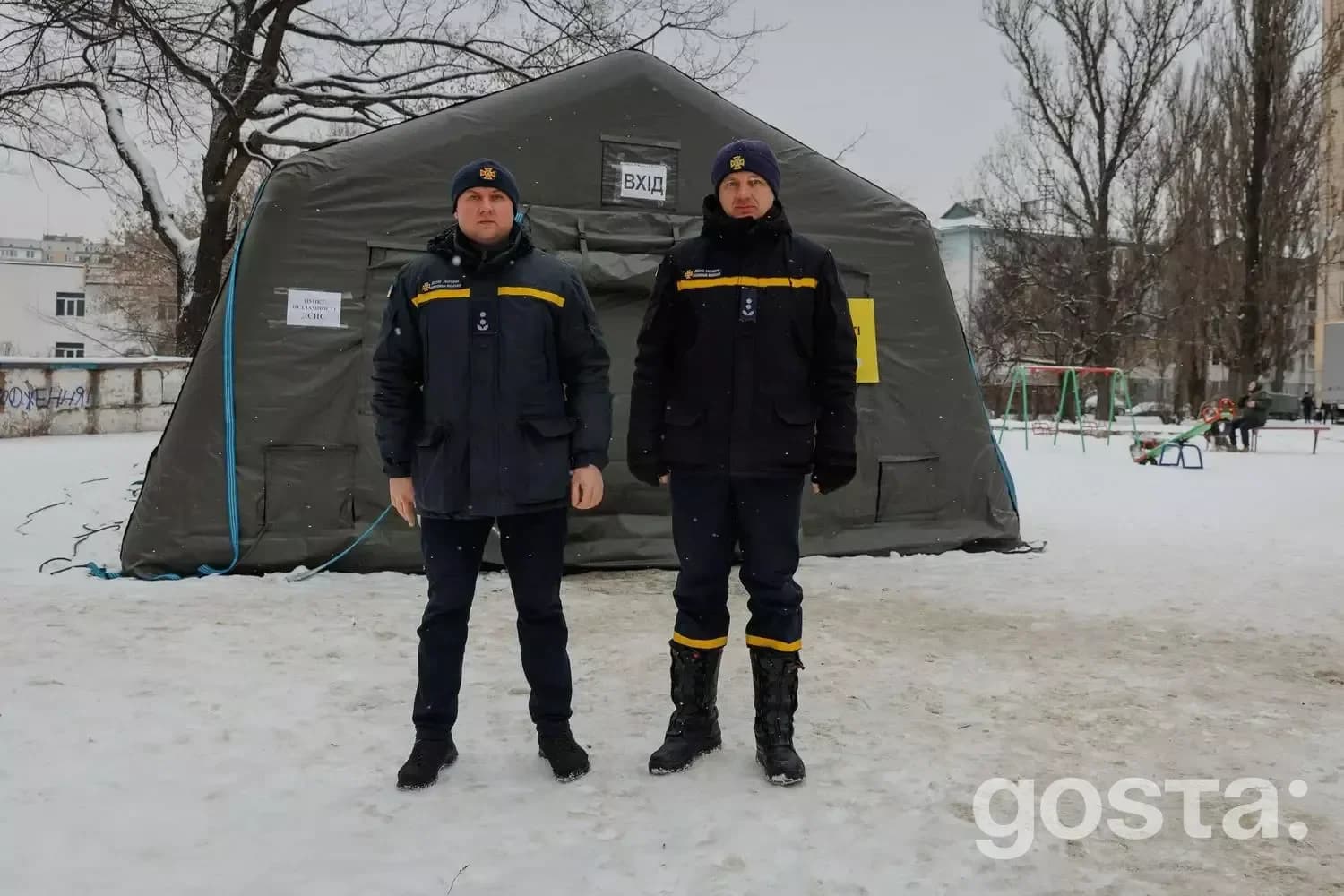 Рятувальники ДСНС України стоять перед наметом екстреної допомоги на снігу під час надзвичайної ситуації.