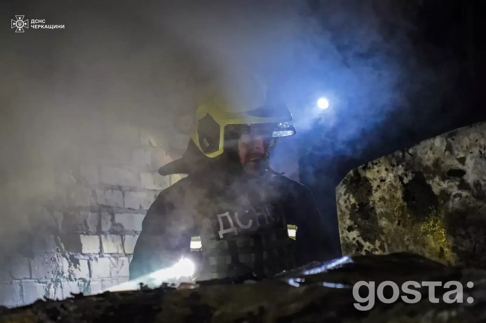 Рятувальник у захисному одязі працює серед диму після обстрілу, ліквідація наслідків атаки в Україні.