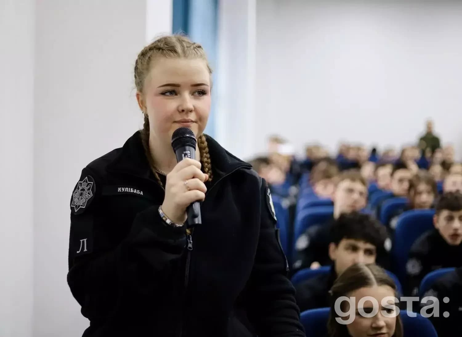 На фото дівчина з мікрофоном виступає перед аудиторією ліцеїстів МВС в Івано-Франківську.