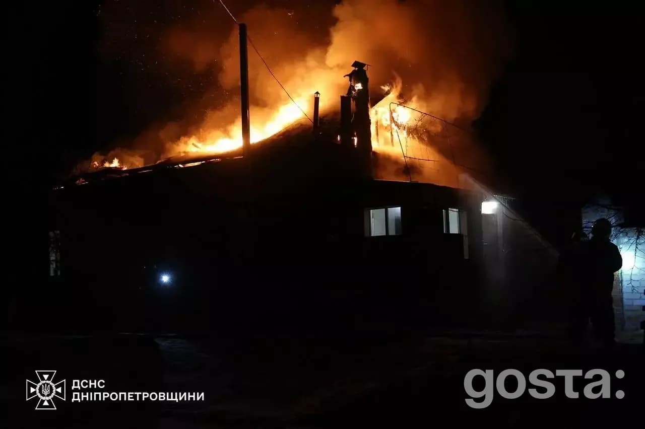 Пожежа в будівлі в Дніпропетровщині спричинена обстрілом, вогнеборці гасять полум'я в нічний час.