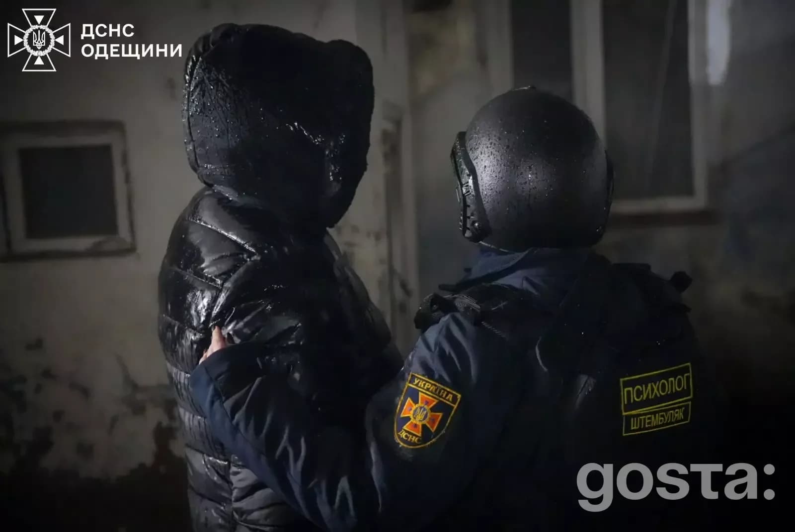 Поліцейський підтримує людину в темному приміщенні після обстрілів в Одеській області, Україна.