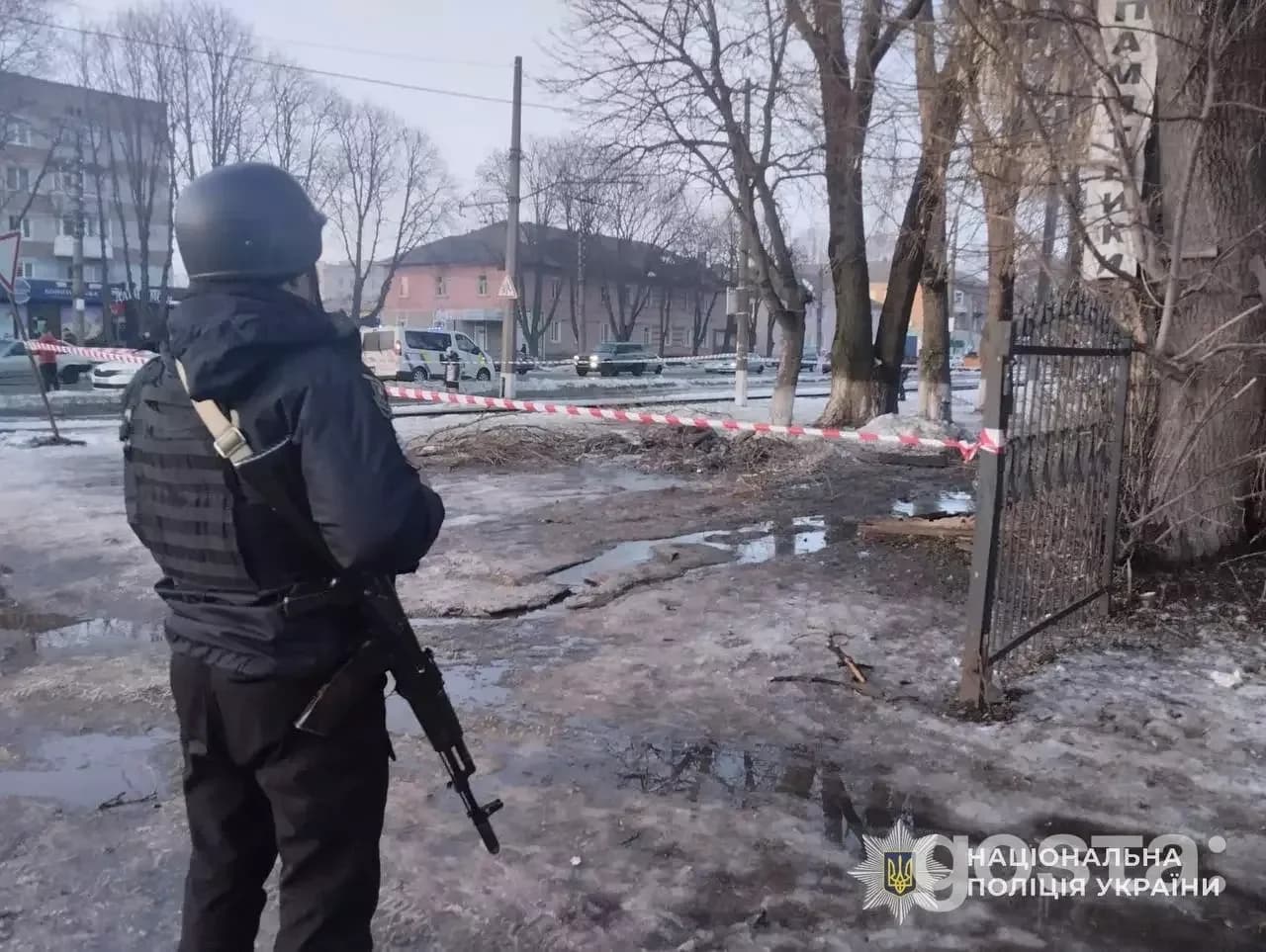 Поліцейський на місці обстрілу в Україні, пошкоджена зона, стрічка обмежує доступ, зима.