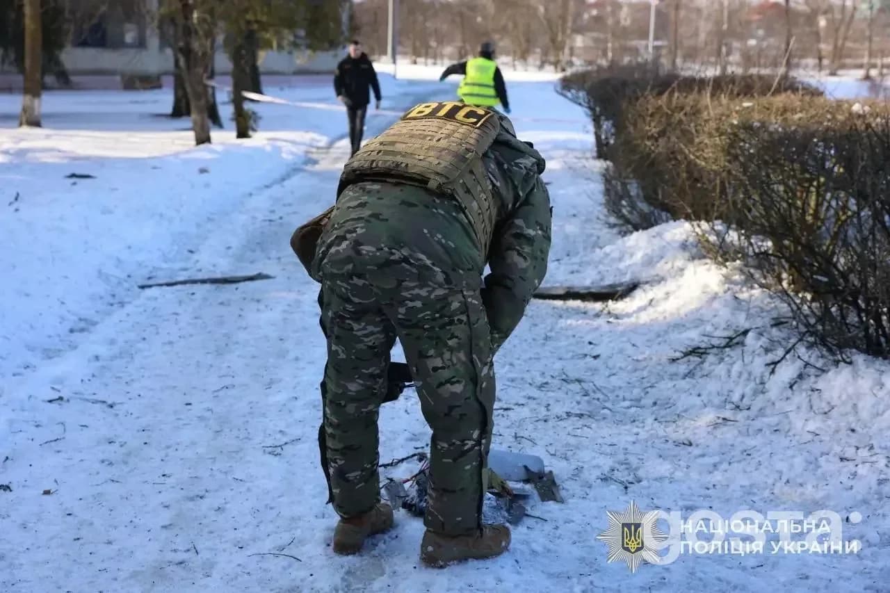 На зображенні поліцейський документує наслідки обстрілу російськими військами взимку; видно сліди атаки на снігу.