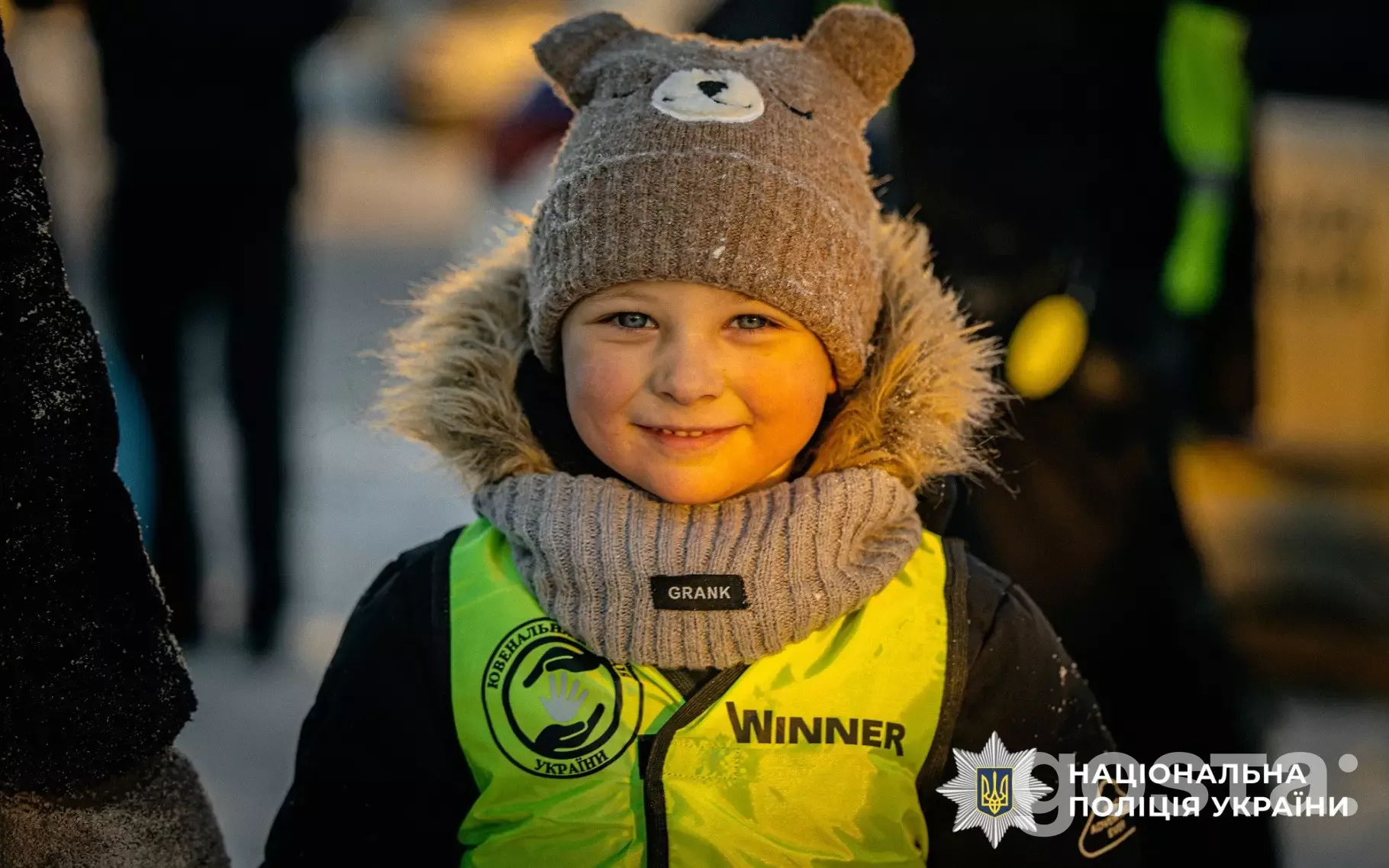 Дитина у яскравому жилеті з логотипом Нацполіції України, зима, профілактичний захід для безпеки.