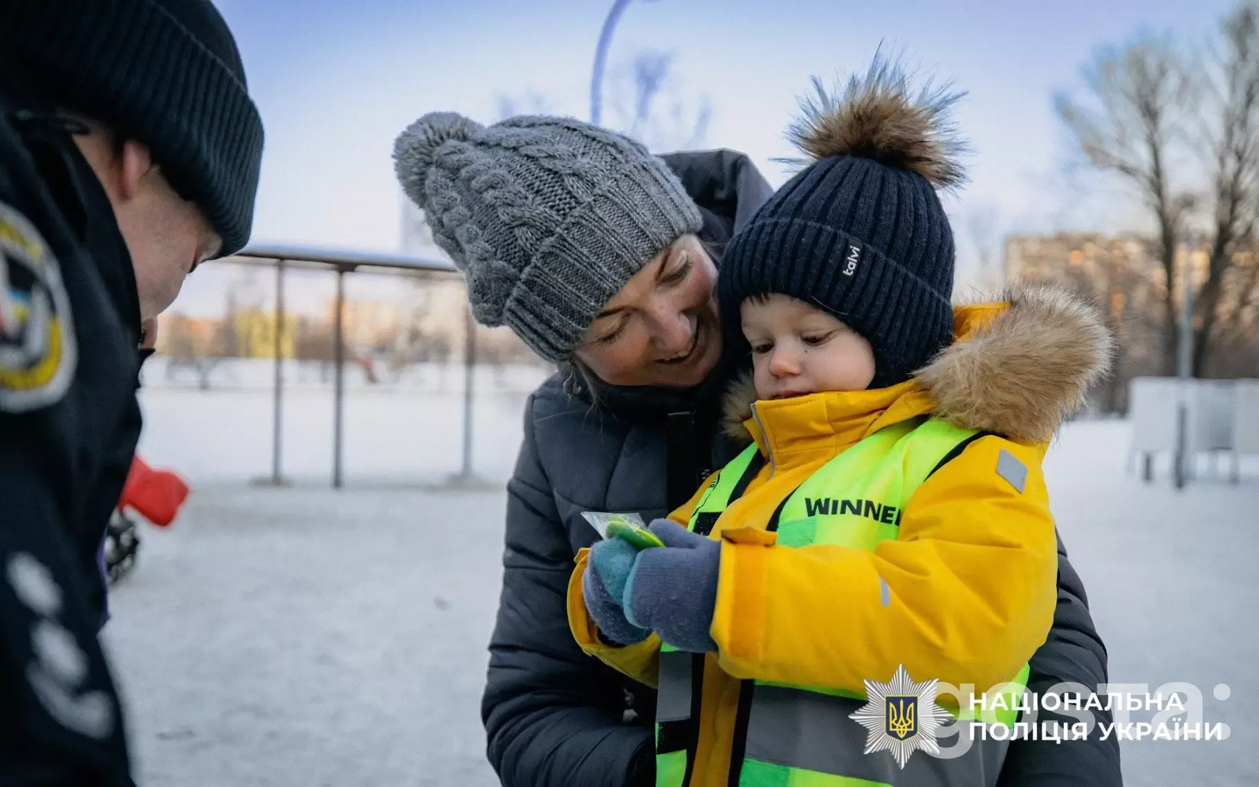 Ювенальні поліцейські роздають світловідбивальні елементи дітям для безпеки на зимових прогулянках у Києві.
