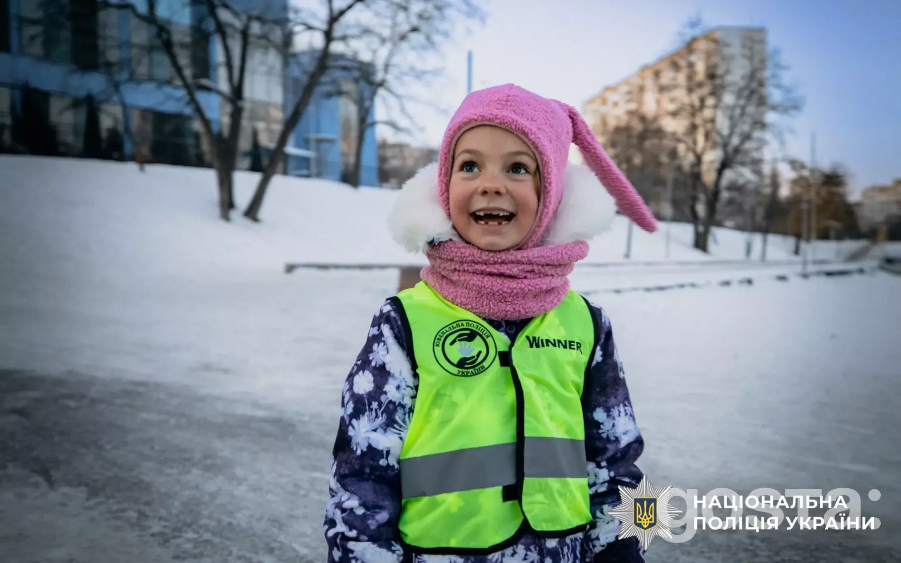 Дитина у світловідбивальному жилеті на зимовій прогулянці в рамках заходів Національної поліції України з безпеки.