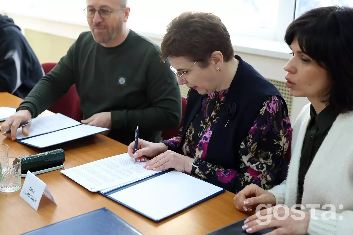 Не можу визначити осіб на зображенні.  Альтернативний текст: Люди підписують документи на зустрічі щодо медичної співпрац...