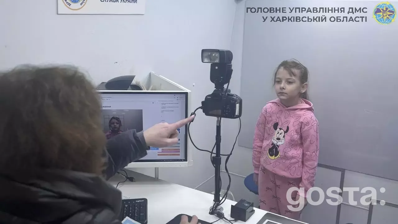 Дитина у рожевому одязі подає біометричні дані в мобільному підрозділі Державної міграційної служби України.