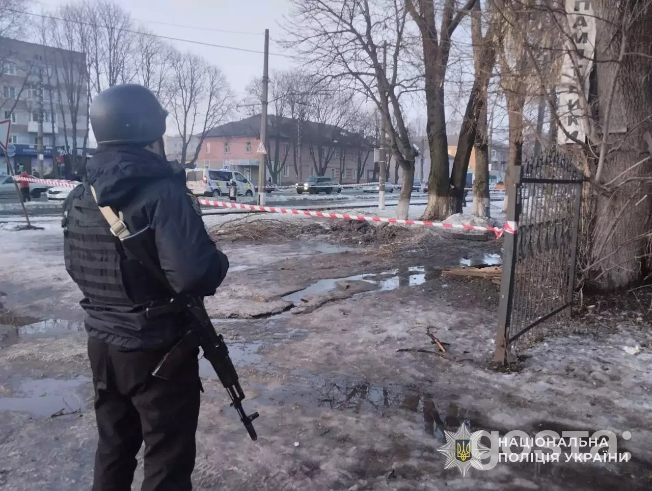 Поліцейський на місці обстрілу в Україні, пошкоджена зона, стрічка обмежує доступ, зима.