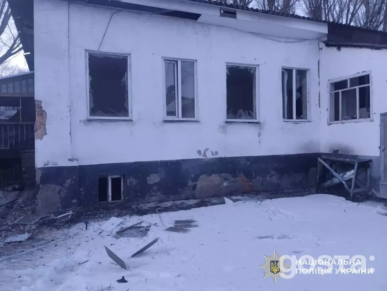 Пошкоджена будівля в результаті обстрілу на Київщині, зимовий пейзаж, робота поліції та рятувальників на місці подій.