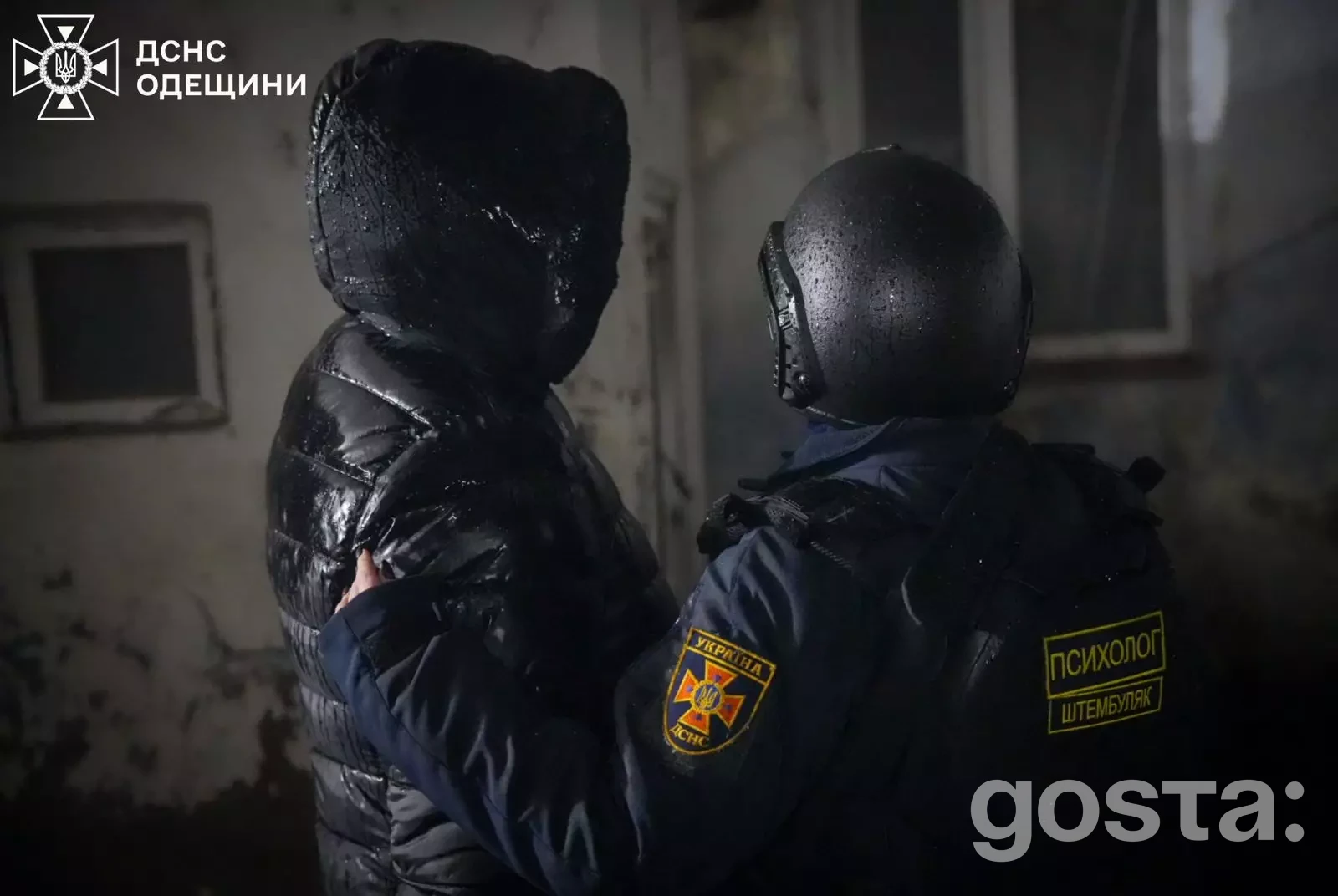 Поліцейський підтримує людину в темному приміщенні після обстрілів в Одеській області, Україна.