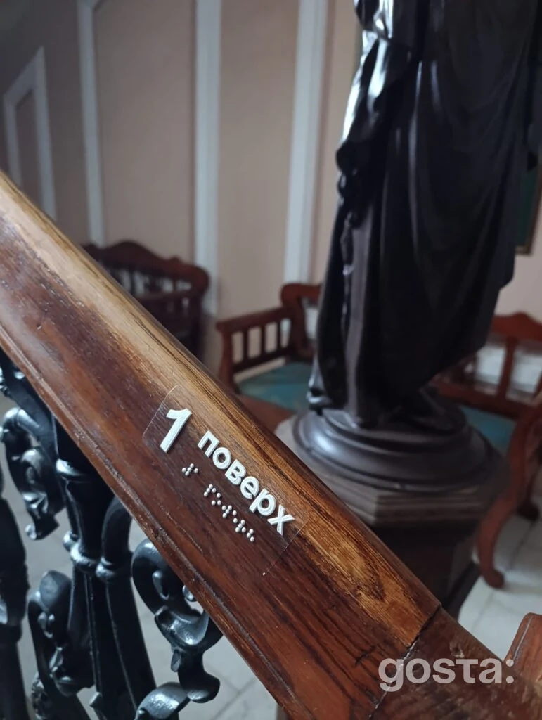 На дерев'яному поручні гравірування шрифтом Брайля, що позначає поверх у Національній філармонії України.