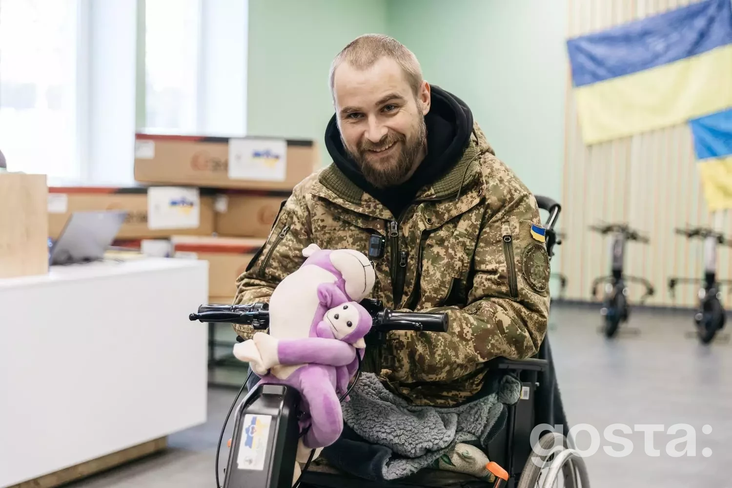 Захисник України на інвалідному візку з електроприводом, тримає іграшку в клініці, демонструючи реабілітацію.