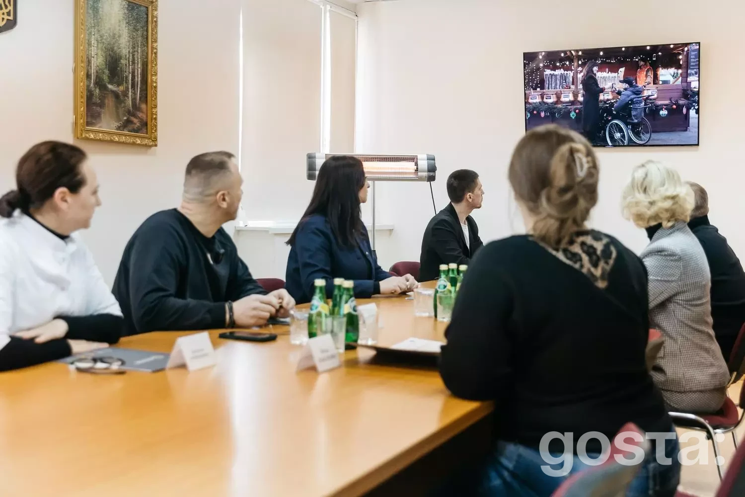 Група людей дивиться презентацію на екрані про використання електроприводів для крісел колісних у реабілітації.