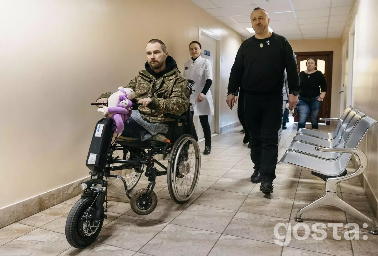 Ветеран у кріслі колісному з електроприводом у коридорі медичного центру, Україна.