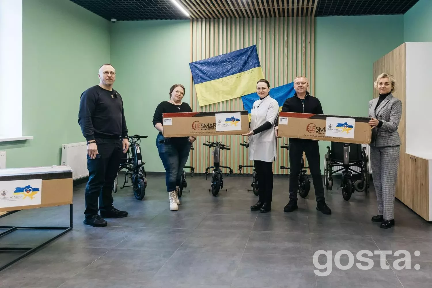 Група людей з коробками для електроприводів в медичному центрі з прапором України.