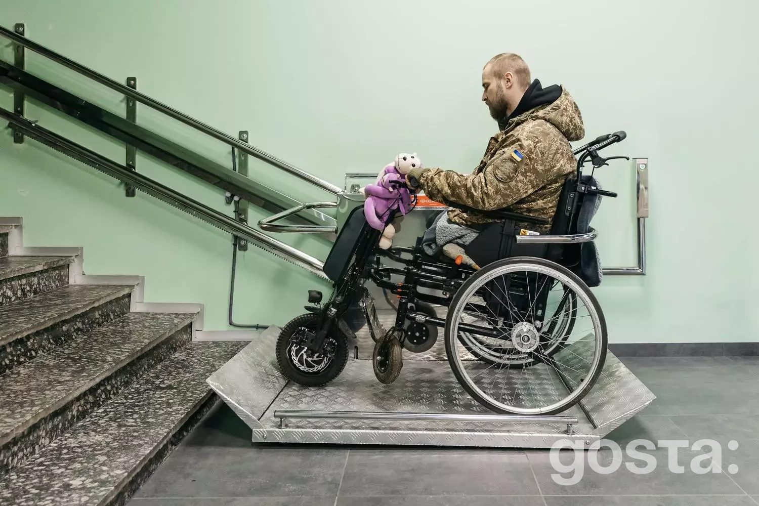 Ветеран в інвалідному візку з електроприводом користується підйомником у медичному центрі, підтримуючи свободу руху.