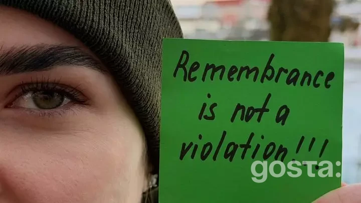 Особа тримає зелений знак із написом "Remembrance is not a violation".