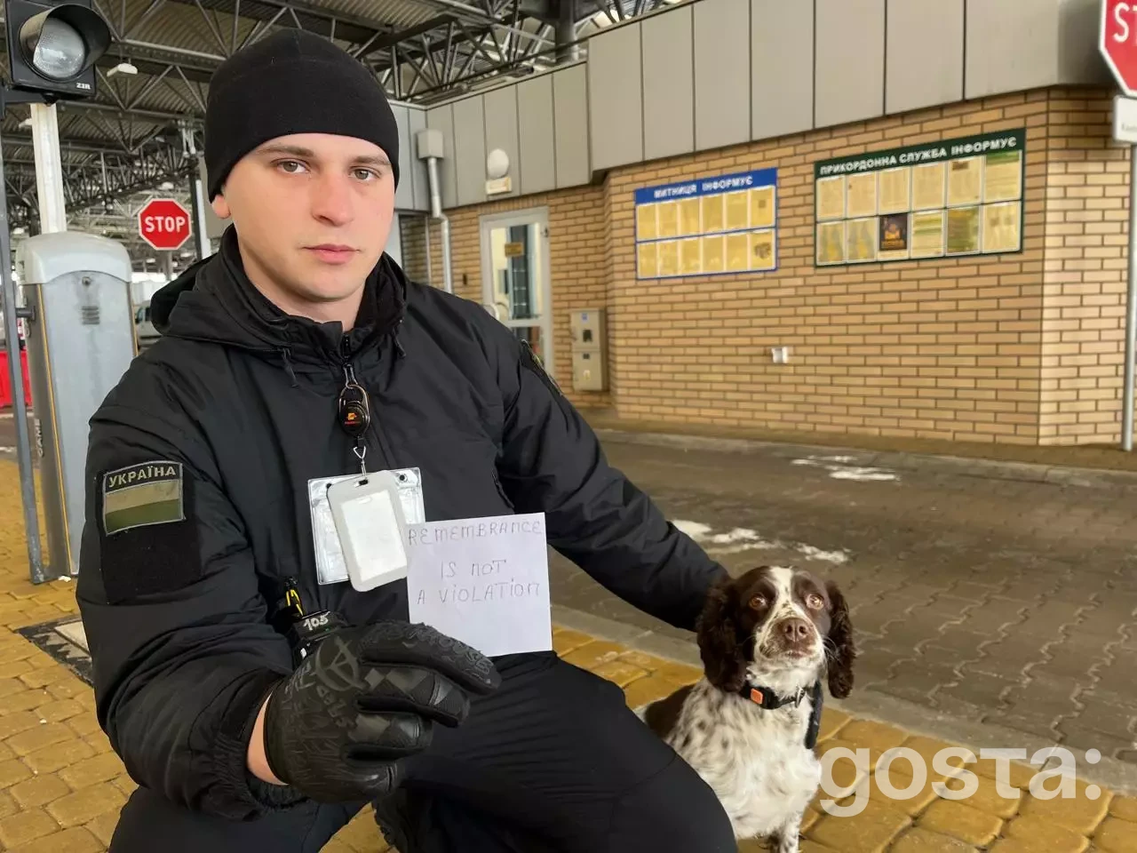На фото: український прикордонник з собакою тримає знак "Remembrance is not a violation".