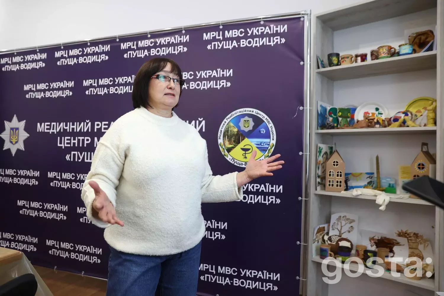 Жінка виступає в реабілітаційному центрі МВС «Пуща-Водиця», поруч - стенд з арт-терапії.