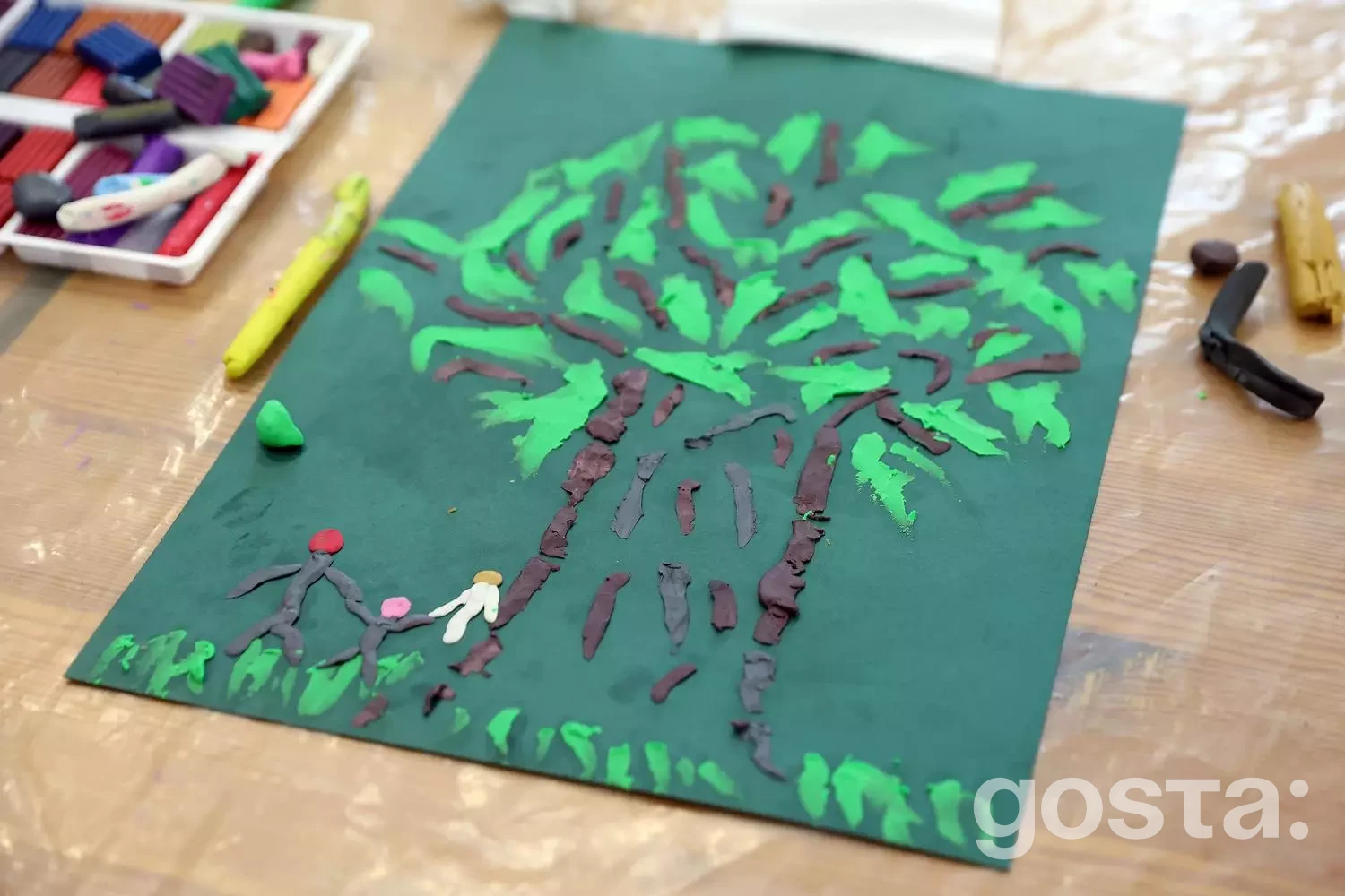 Виріб з пластиліну на зеленому фоні зображає дерево та фігурки людей, символізуючи реабілітацію і підтримку.