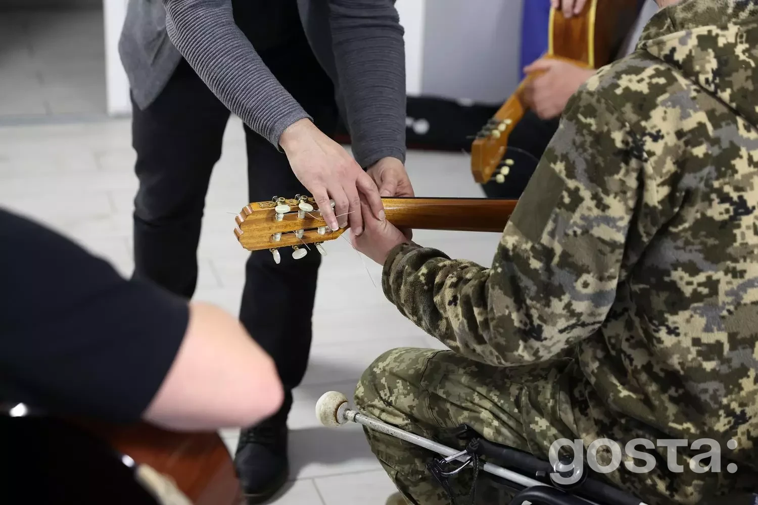 Учасник у військовій формі навчається грі на гітарі в медичному реабілітаційному центрі для ветеранської підтримки.