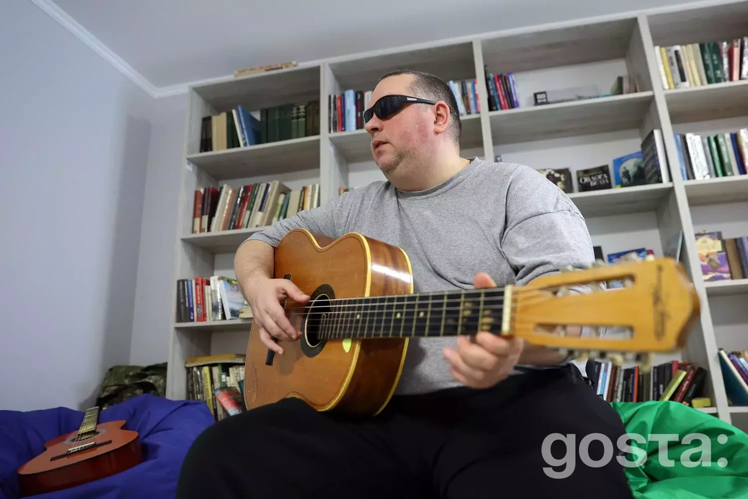 Людина грає на гітарі в реабілітаційному центрі, підкреслюючи важливість музики в терапії ветеранів з втратою зору.