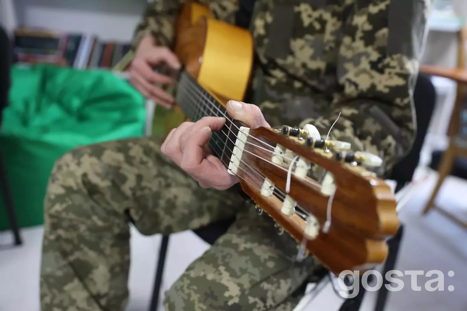 Ветеран у камуфляжі грає на гітарі в реабілітаційному центрі, підтримка через музику.