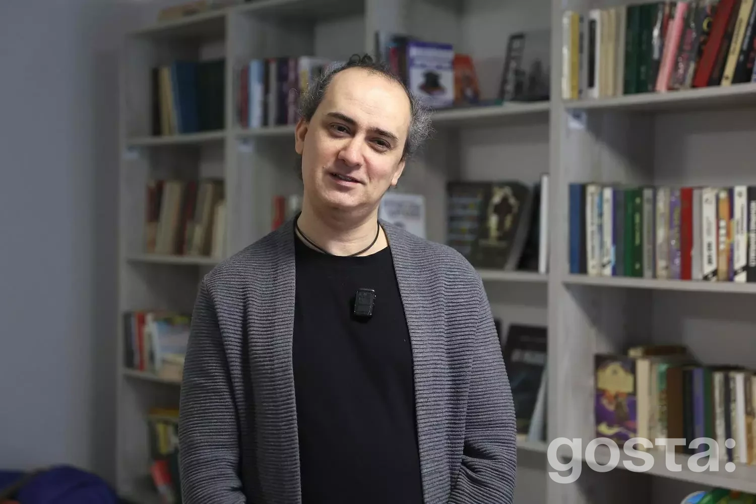 На зображенні чоловік у медичному реабілітаційному центрі «Пуща-Водиця» на тлі книжкових полиць.