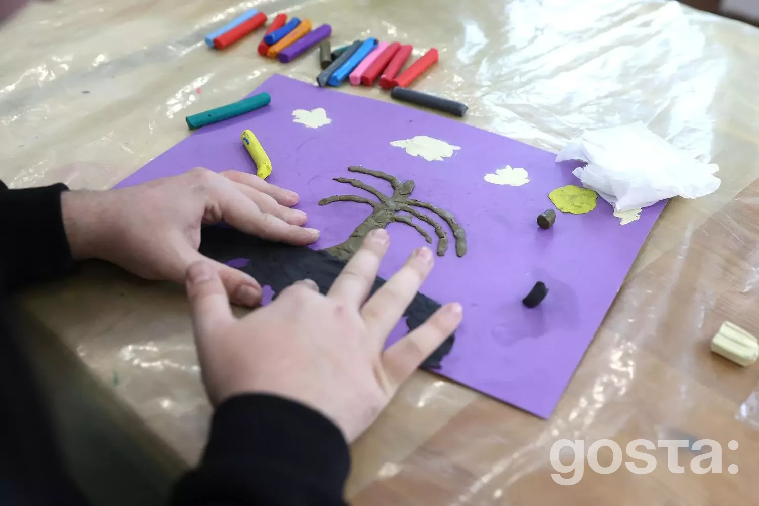 Людина створює арт-терапію, ліплячи дерево на фіолетовому папері в реабілітаційному центрі МВС України.