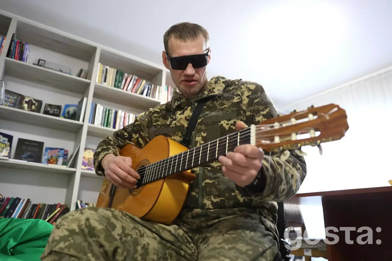 Ветеран у формі грає на гітарі в реабілітаційному центрі, що символізує нові можливості для адаптації.