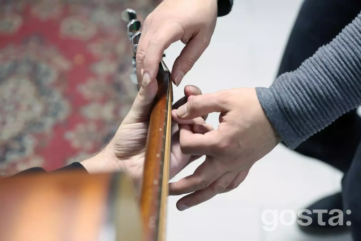 Людина навчається грати на гітарі під керівництвом інструктора, включаючись у процес реабілітації ветеранів.