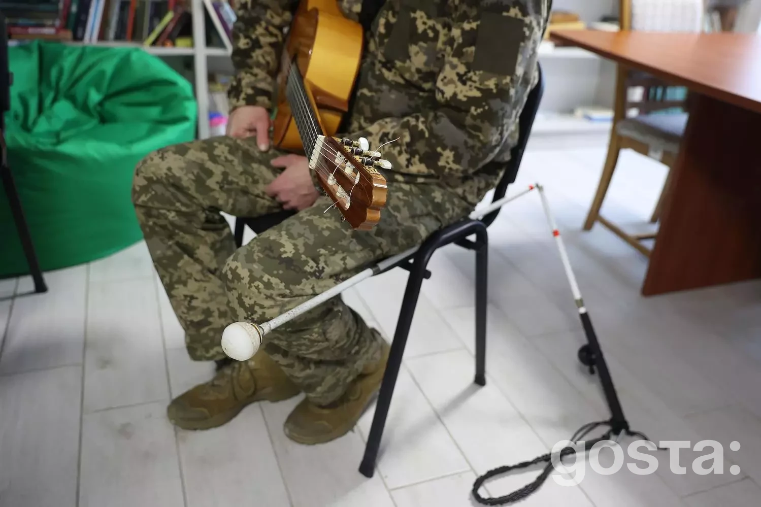 Ветеран у камуфляжі грає на гітарі в реабілітаційному центрі, навчаючись нових навичок для соціальної інтеграції.