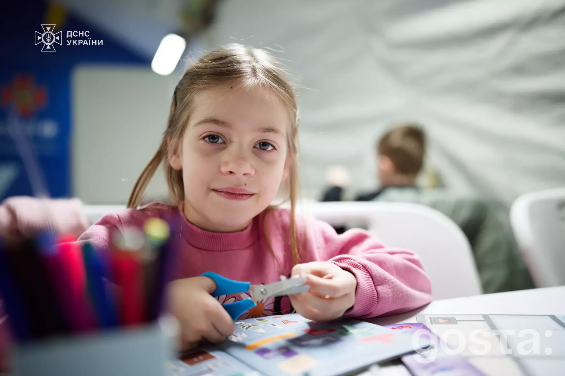 Дівчинка в мобільному пункті незламності ДСНС, займається творчістю під час психосоціальної підтримки ЮНІСЕФ.