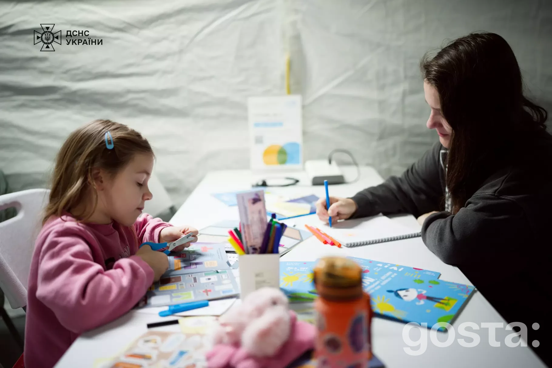 Дитина та дорослий займаються творчістю у мобільному пункті незламності ДСНС та ЮНІСЕФ, отримуючи психосоціальну підтримку.