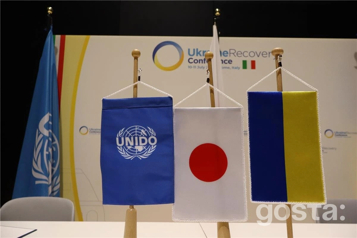 Прапори ЮНІДО, Японії та України на конференції відновлення, що символізує партнерство для промислового розвитку.